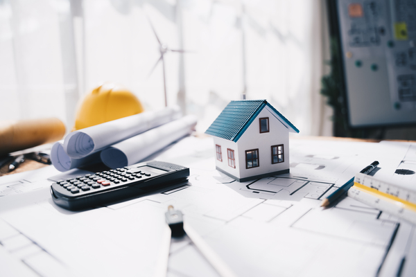 Calculator, house model, and blueprints showing mortgage refinance costs near me