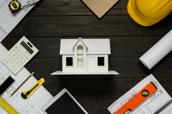 Flat lay of house model with blueprints, calculator, and construction tools for remodeling projects, connected to mortgage calculator credit karma Experian financial planning.