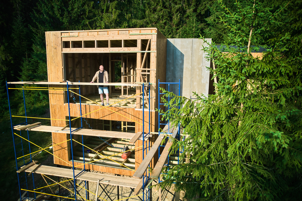 Building a Deck and Wooden House Frame in Forest Forest-side wood deck construction featuring composite decking boards and timber framing near patio deck area.