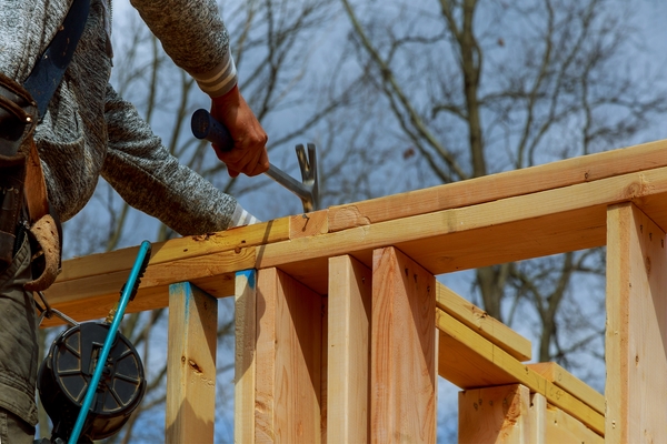 Close-up of a carpenter working on deck joist and wood framing using composite deck materials.