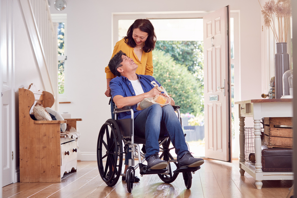 Handicap Accessible Apartments with Proper ADA Door Width Woman pushing a man in a wheelchair through handicap accessible home entry with ADA compliant doors.
