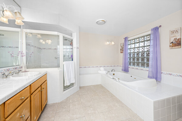 Large jetted tub with nearby shower stall in a white bathroom remodel setting
