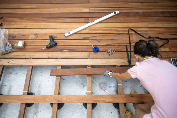 DIY Deck Construction in Progress Woman building a backyard wooden deck using treated wood boards