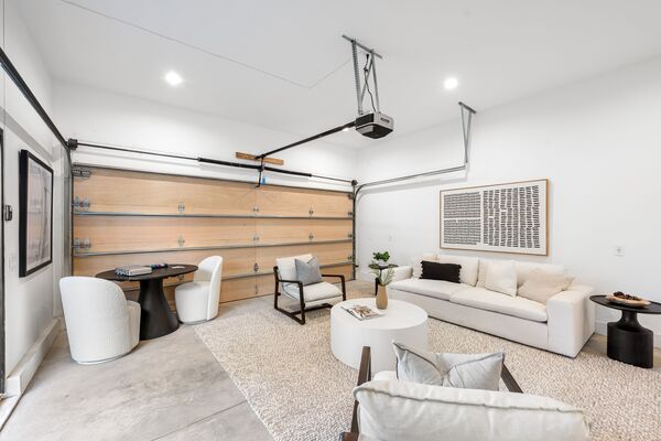 Modern garage conversion into living space featuring Clopay garage door, cozy furniture, and artwork