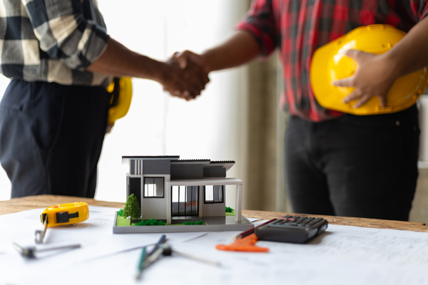 Handshake over home model showing home building assistance programs