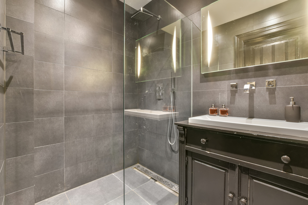 Stylish bathroom with dark tiles, glass shower enclosure, and vanity, an example for images of bathroom makeovers and remodeled bathroom images