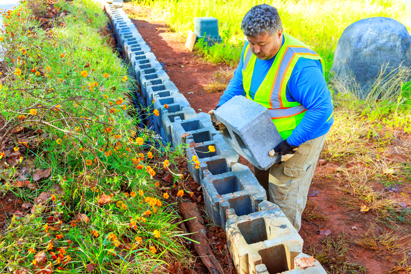 Worker installing belgard versa lok blocks for landscape barrier wall
