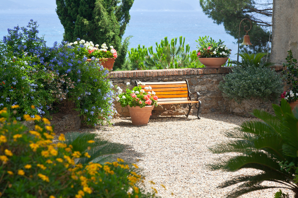 Peaceful courtyard with bench, flowering pots, and gravel representing landscape design services and landscape edging