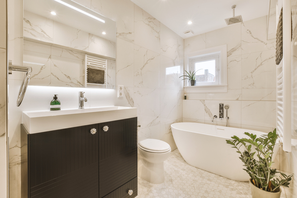 Luxurious bathroom featuring a free-standing tub, black vanity, and marble walls – master bathroom tile ideas 2023