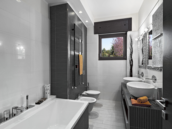 Stylish modern bathroom featuring dual sinks, bathtub, and black tile accents, ideal for homeowners using fha loan interest rates today for renovations.