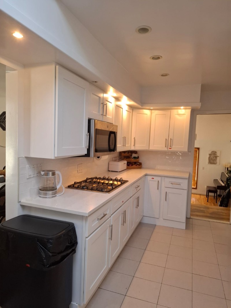 Professional kitchen remodel showcasing white kitchen cabinets, gas range installation, quartz countertops, recessed lighting, and efficient L-shaped kitchen layout