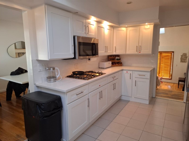 Finished kitchen remodel with white shaker style cabinets, quartz countertops, gas range, under cabinet lighting, and professional kitchen design layout