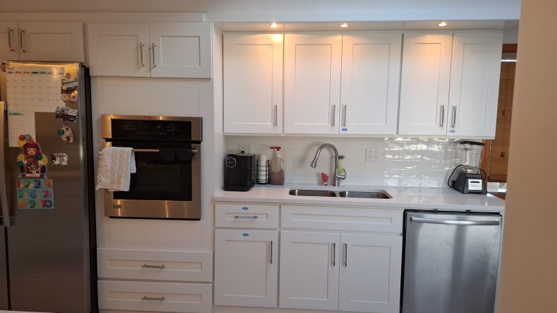 Kitchen remodeling project with white cabinets, stainless steel wall oven, undermount sink, subway tile backsplash, and integrated dishwasher installation